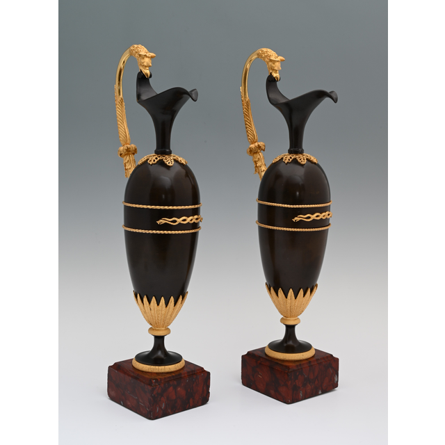 A pair of French Empire patinated bronze and ormolu ewers